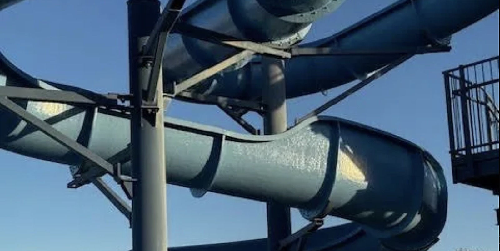 Refinished blue slide wrapping around its steel tower against a clear sky in Burlington, Colorado