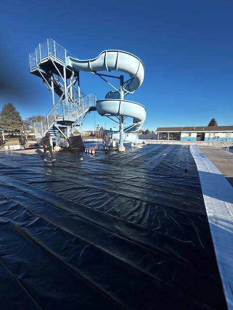 Pool deck and basin covered in protective sheeting below the slide tower
