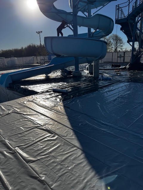 Crew member on the spiral slide with the pool fully covered below