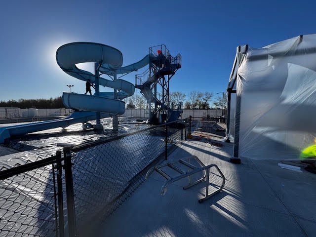 Slide tower and covered pool deck with a nearby structure wrapped in plastic
