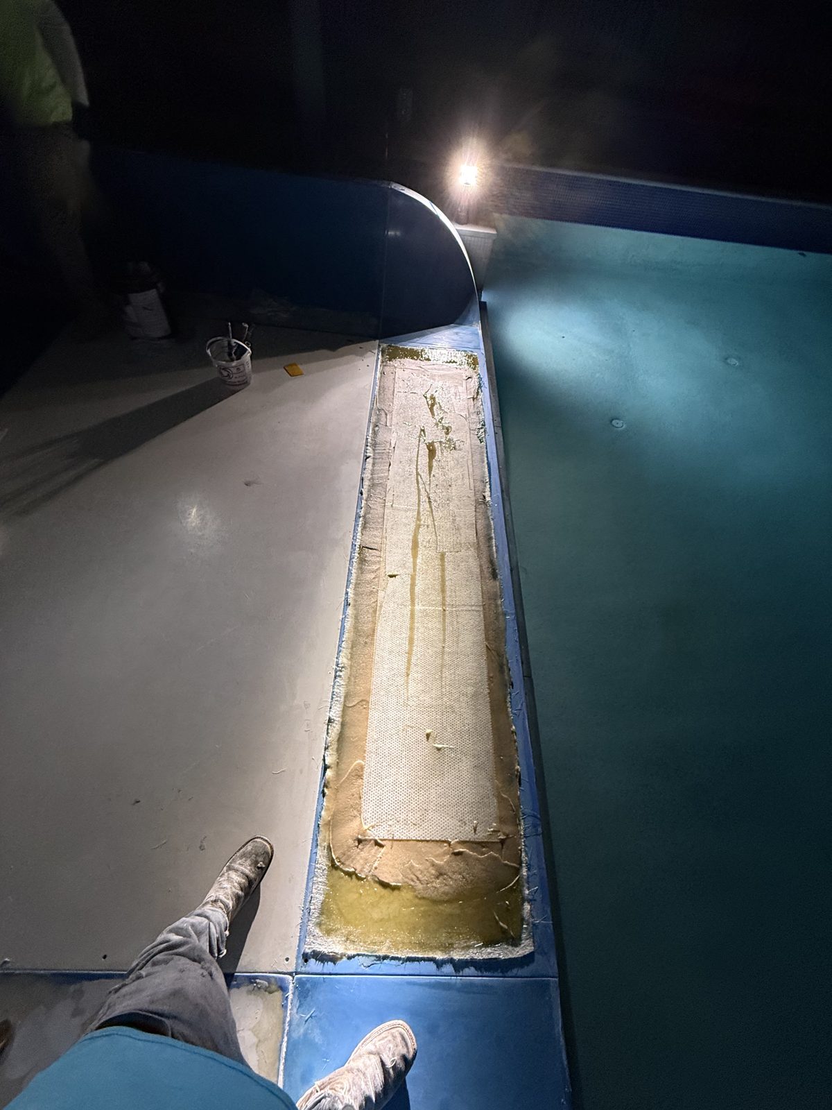 Fiberglass repair along a slide seam under work lights